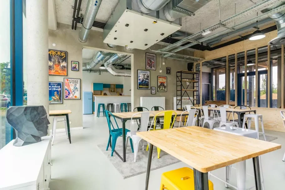 espace de vie Espace intérieur moderne avec tables en bois, chaises colorées et œuvres d'art au mur.