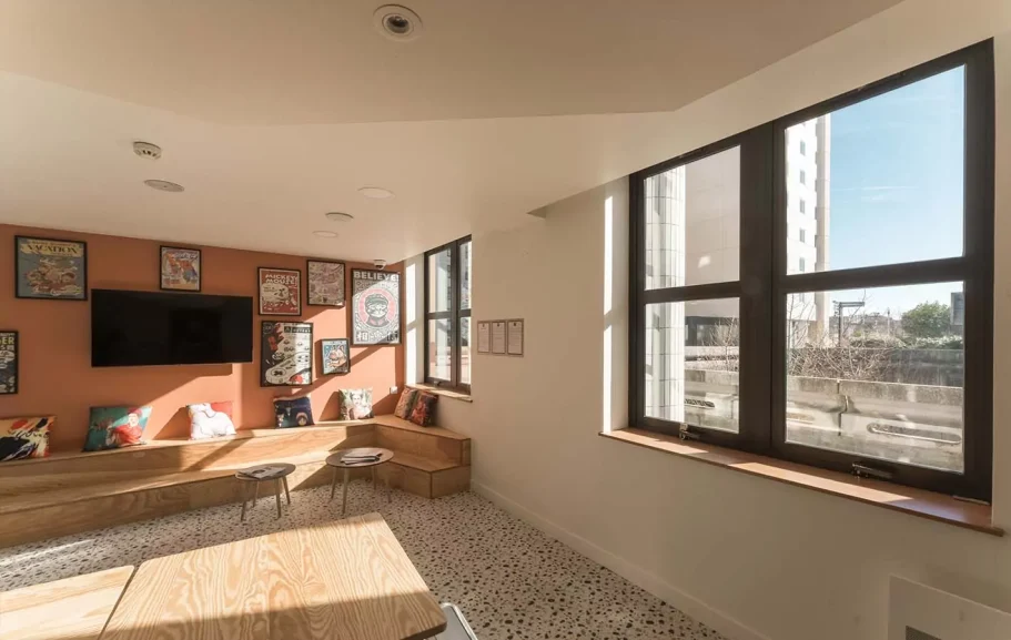 Coin salon Intérieur d'un salon lumineux avec fenêtres, murs orange et mobilier en bois.