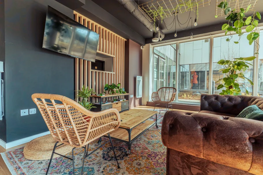 coin salon Salon moderne avec fauteuil en rotin, canapé marron, télévision et plantes d'intérieur.