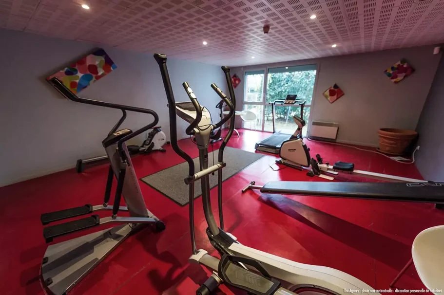 salle de sport Salle de sport avec plusieurs appareils de fitness sur un sol rouge.