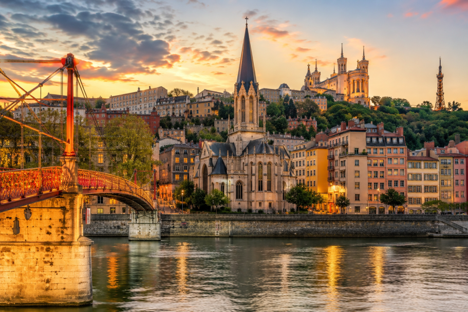 Vue de la ville de Lyon au coucher du soleil, avec une église et un pont pittoresque.