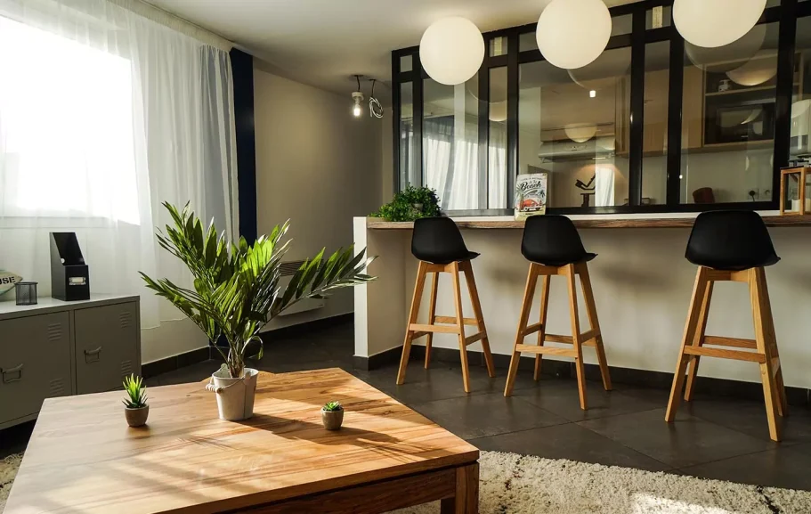 cuisine Intérieur moderne avec bar, chaises hautes, plantes et lumière naturelle.