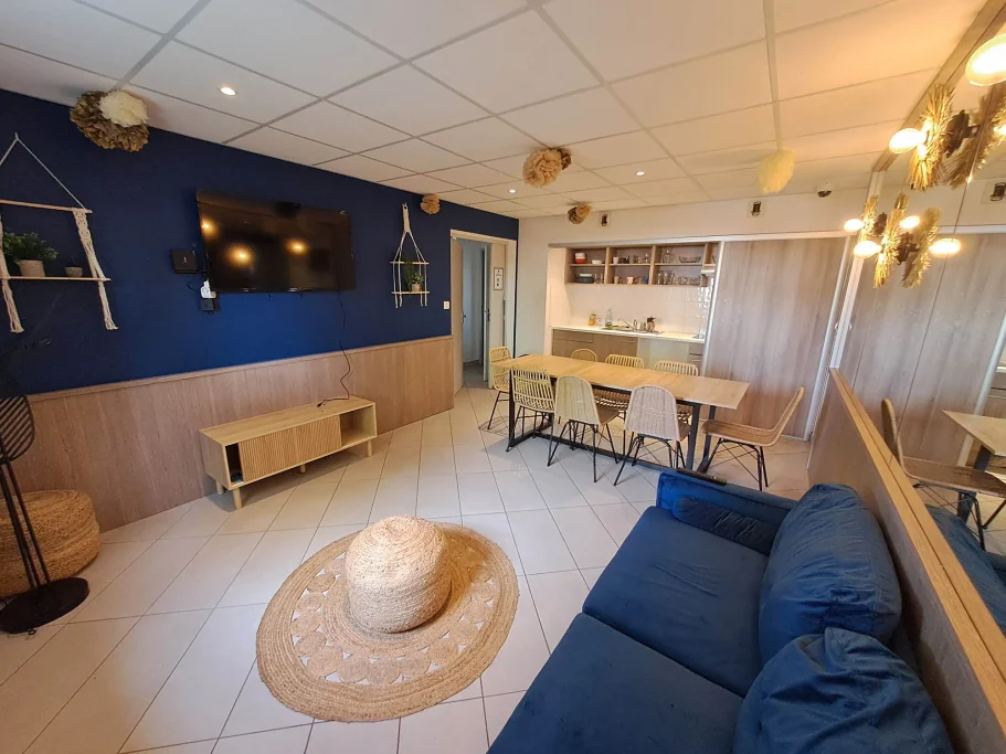 Studio Salon moderne avec mur bleu, canapé, table de salle à manger et cuisine ouverte.