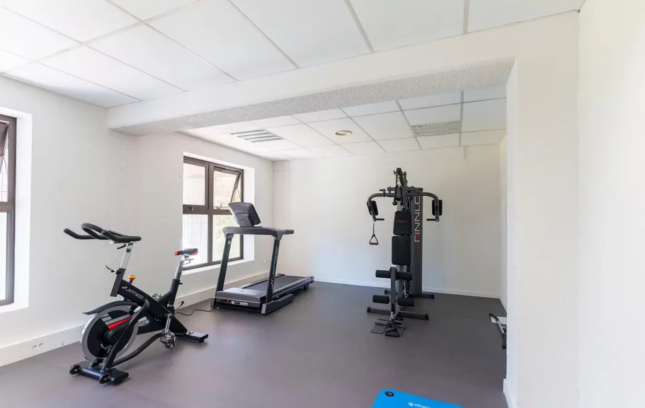 Salle de sport Salle de sport avec un vélo d'appartement, un tapis de course et une machine de musculation.