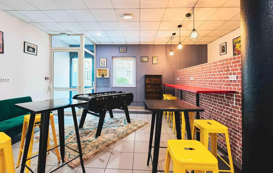 Coin détente Espace intérieur moderne avec tables hautes, chaises jaune et coin de jeux.