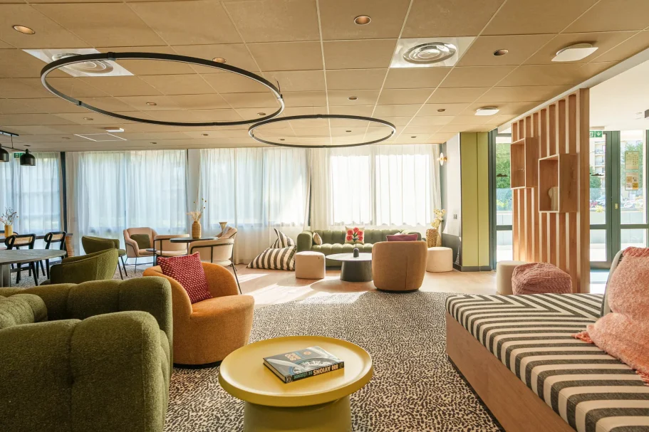 espace détente Intérieur moderne et lumineux avec des fauteuils colorés et des luminaires circulaires.