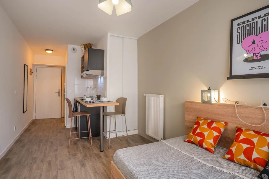 studio Chambre moderne avec lit, cuisine et décor minimaliste aux murs clairs.